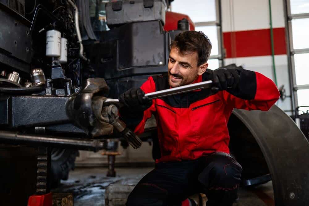 Experienced mechanic changing wheels on tractor.