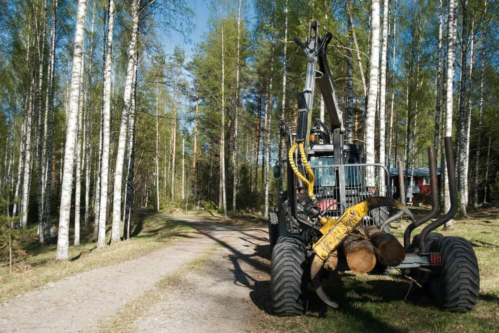 Harvester in the forest path with logs.